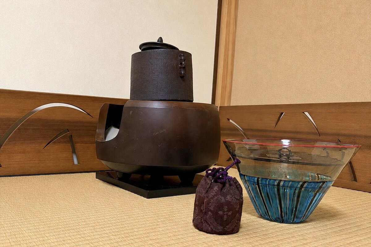 茶室の畳に置かれた風炉と釜、ガラスの水指、仕覆に入った茶入