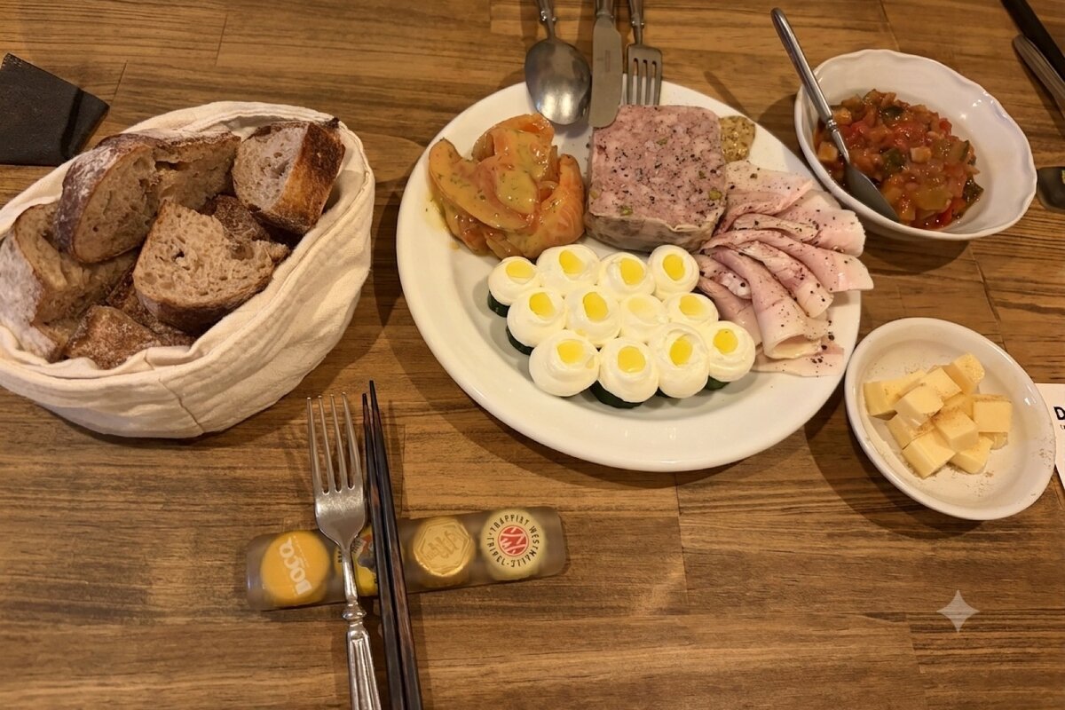 パテ、ハム、サーモンのマリネ、きゅうりの上の卵が並んだ前菜の盛り合わせと、切ったパンの籠